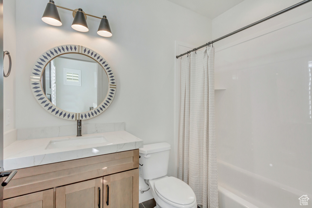 Bathroom with toilet, vanity, and shower / bathtub combination with curtain