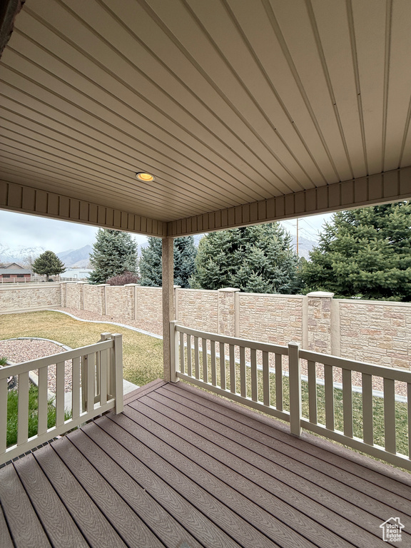 Wooden terrace featuring a fenced backyard, a lawn, and a mountain view
