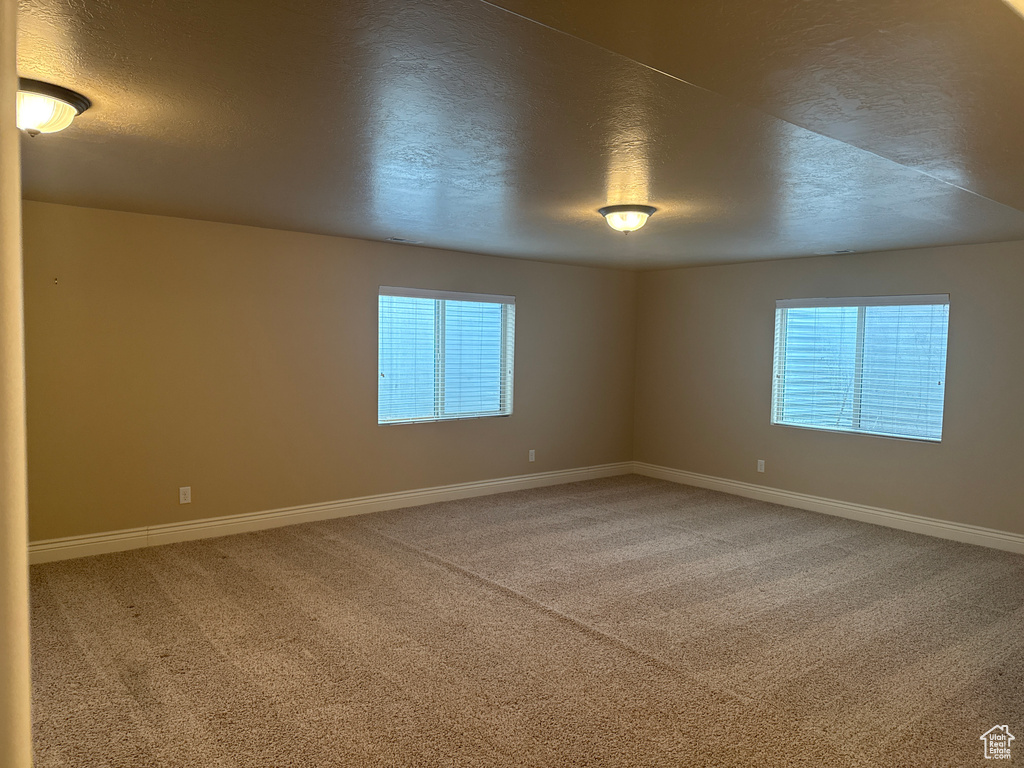 Spare room featuring baseboards, a textured ceiling, and carpet