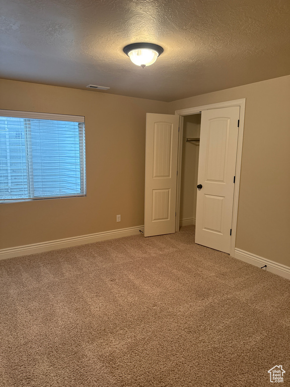 Unfurnished bedroom with carpet floors, a textured ceiling, baseboards, and visible vents