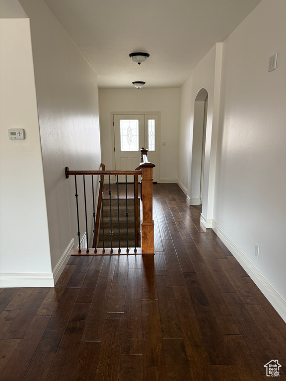 Hallway featuring arched walkways, dark wood-style floors, and baseboards