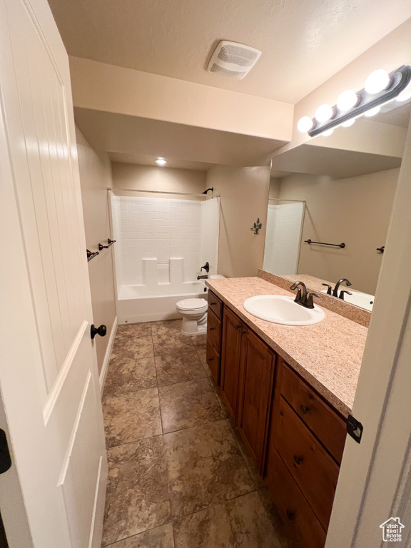 Bathroom with bathtub / shower combination, toilet, vanity, a textured ceiling, and visible vents