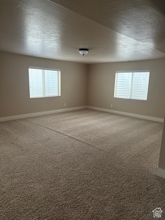 Carpeted empty room featuring baseboards and a textured ceiling