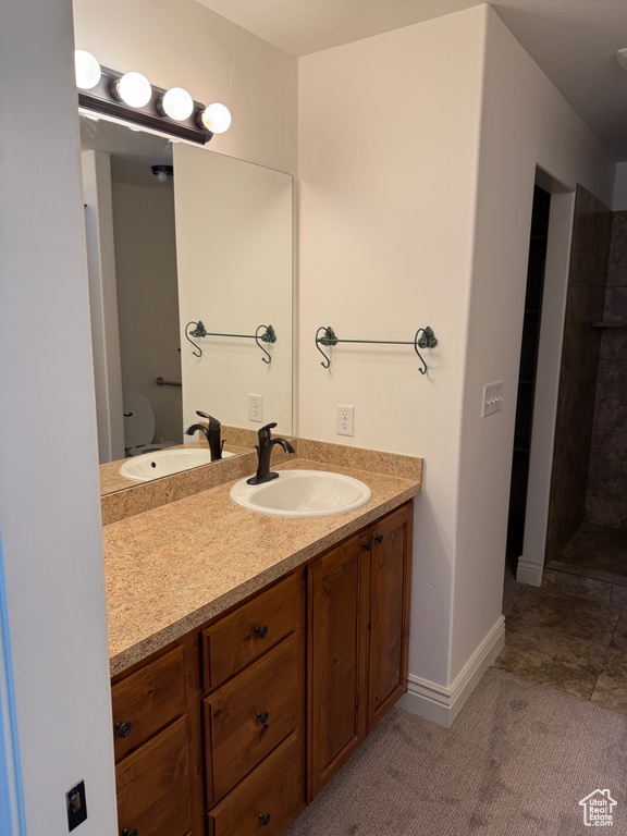 Full bathroom with baseboards, tiled shower, and vanity