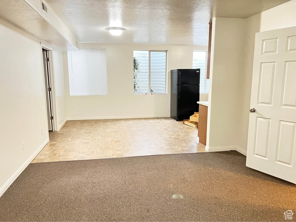 Empty room with light colored carpet and a textured ceiling