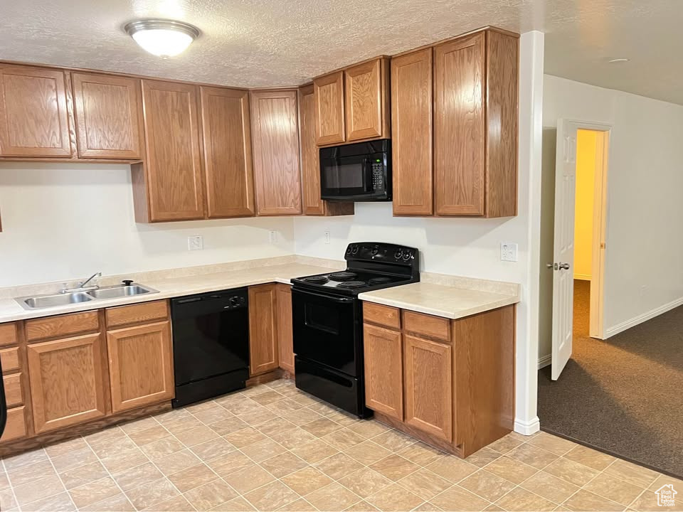 Kitchen with black appliances, light countertops, and brown cabinets