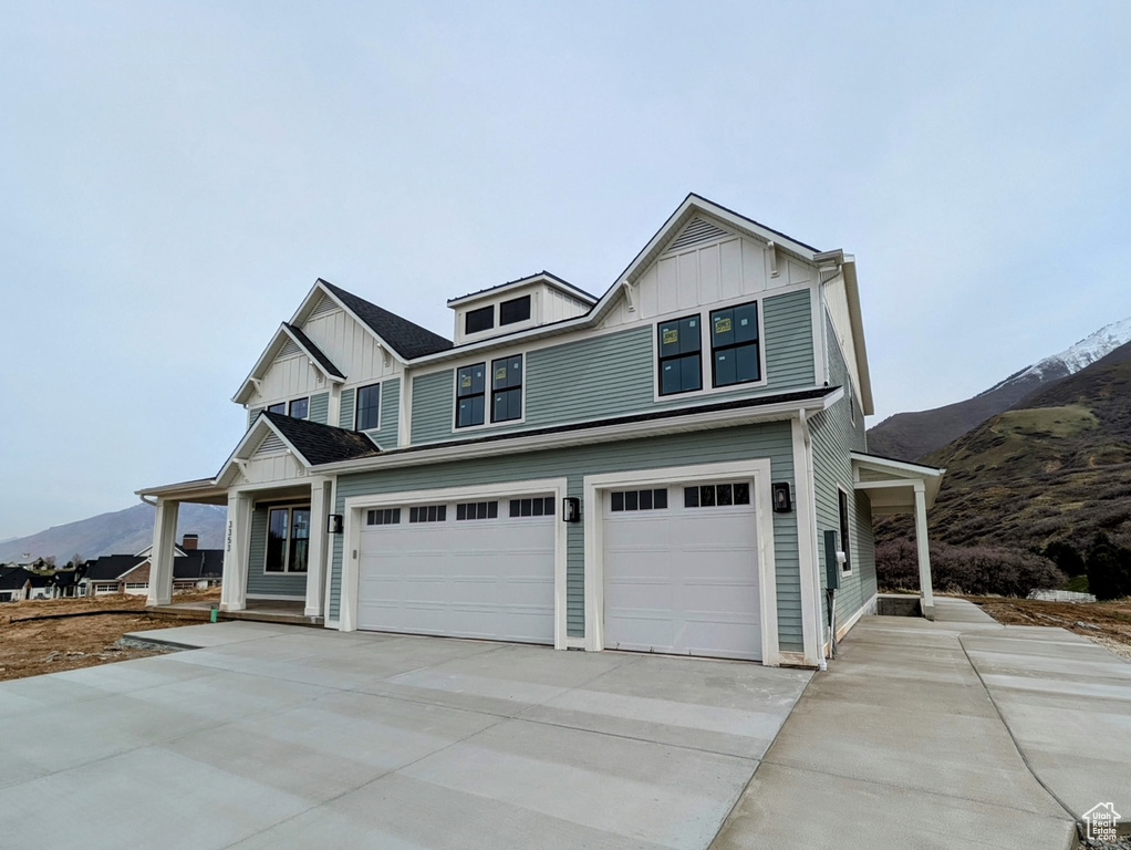 View of front facade with board and batten siding, driveway, a mountain view, and an attached garage