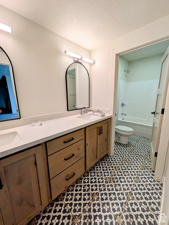 Full bath with double vanity, a sink, and toilet