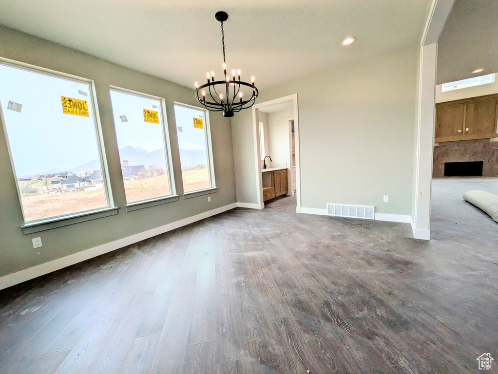 Unfurnished dining area featuring a notable chandelier, wood finished floors, baseboards, visible vents, and recessed lighting