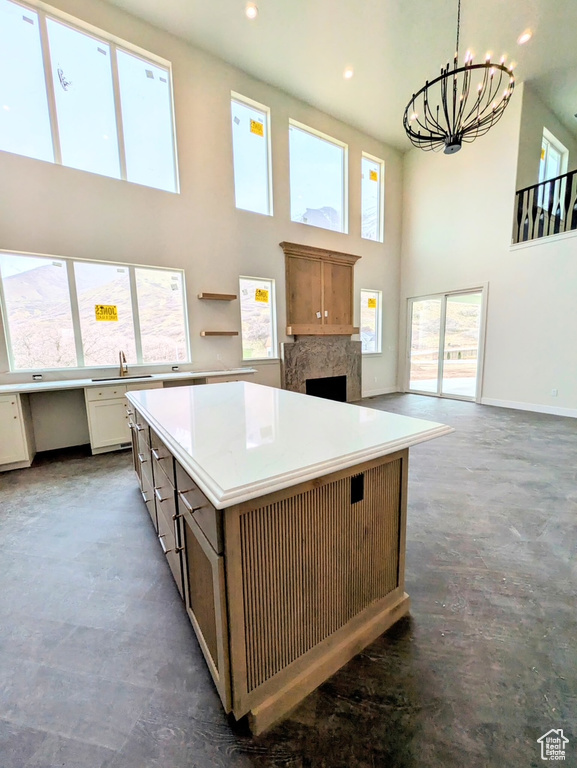 Kitchen featuring light countertops, a premium fireplace, a chandelier, a kitchen island, and a towering ceiling