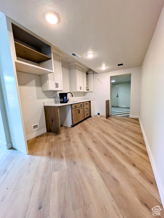 Kitchen with open shelves, baseboards, light wood finished floors, and visible vents