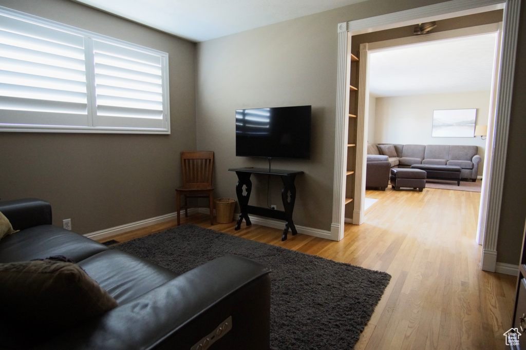 Living area with baseboards, a healthy amount of sunlight, and wood finished floors