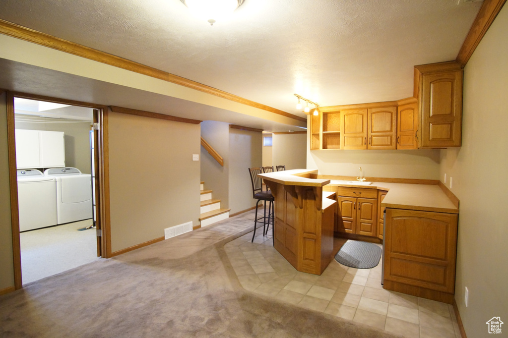 Kitchen with open shelves, light carpet, a breakfast bar area, washing machine and clothes dryer, and visible vents