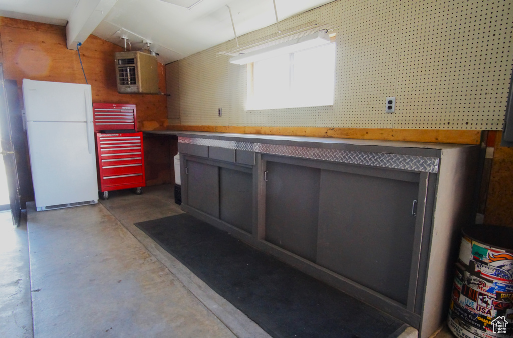 Interior space with concrete flooring, lofted ceiling with beams, and freestanding refrigerator