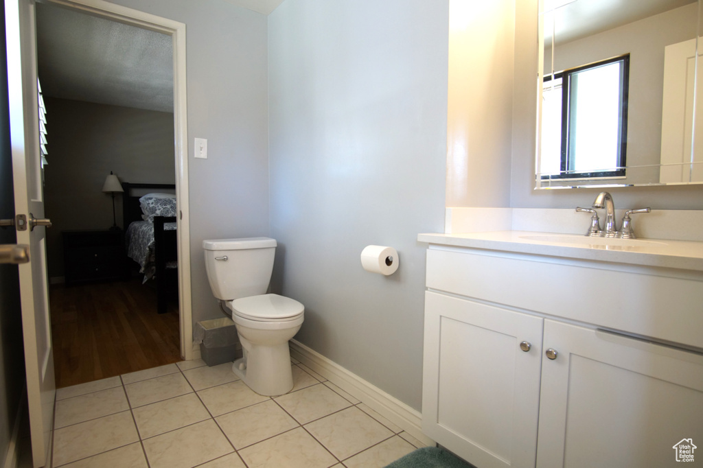 Bathroom featuring tile patterned floors, toilet, baseboards, and vanity