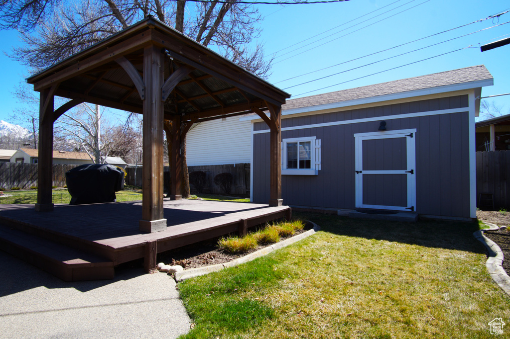 View of yard featuring an outdoor structure, a gazebo, fence, and a wooden deck
