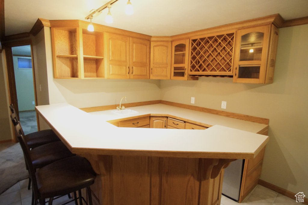 Kitchen with glass insert cabinets, a breakfast bar area, a sink, and a peninsula