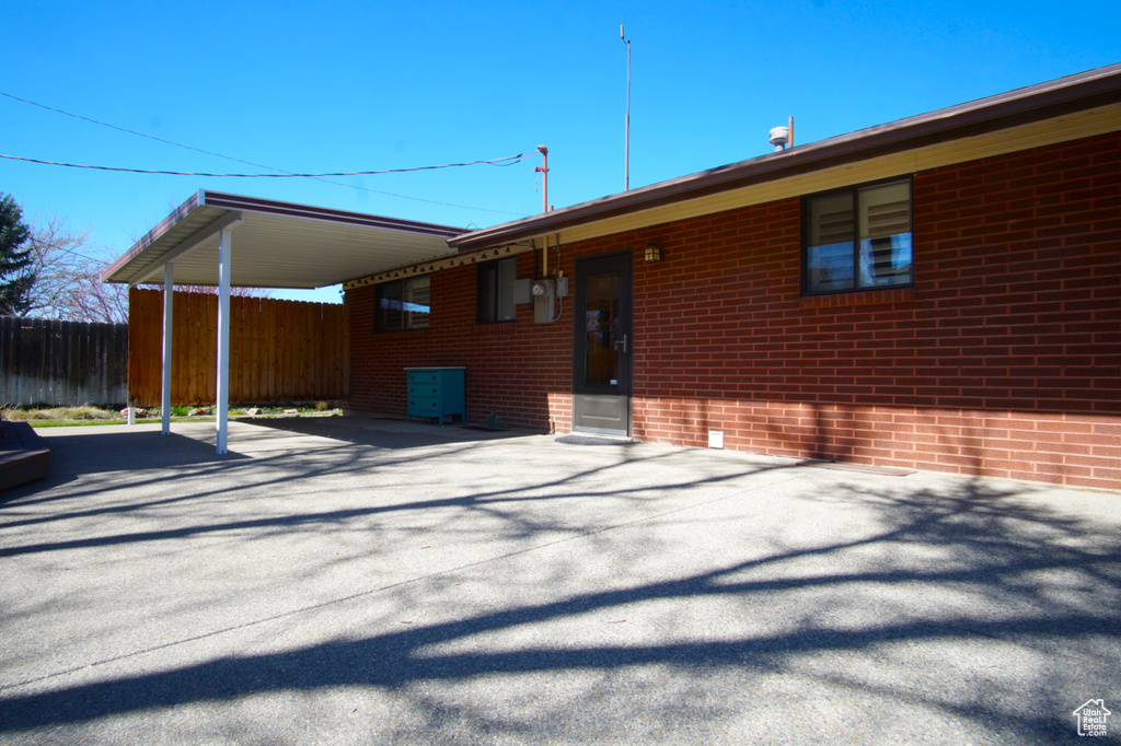 Rear view of property with an attached carport, brick siding, and fence