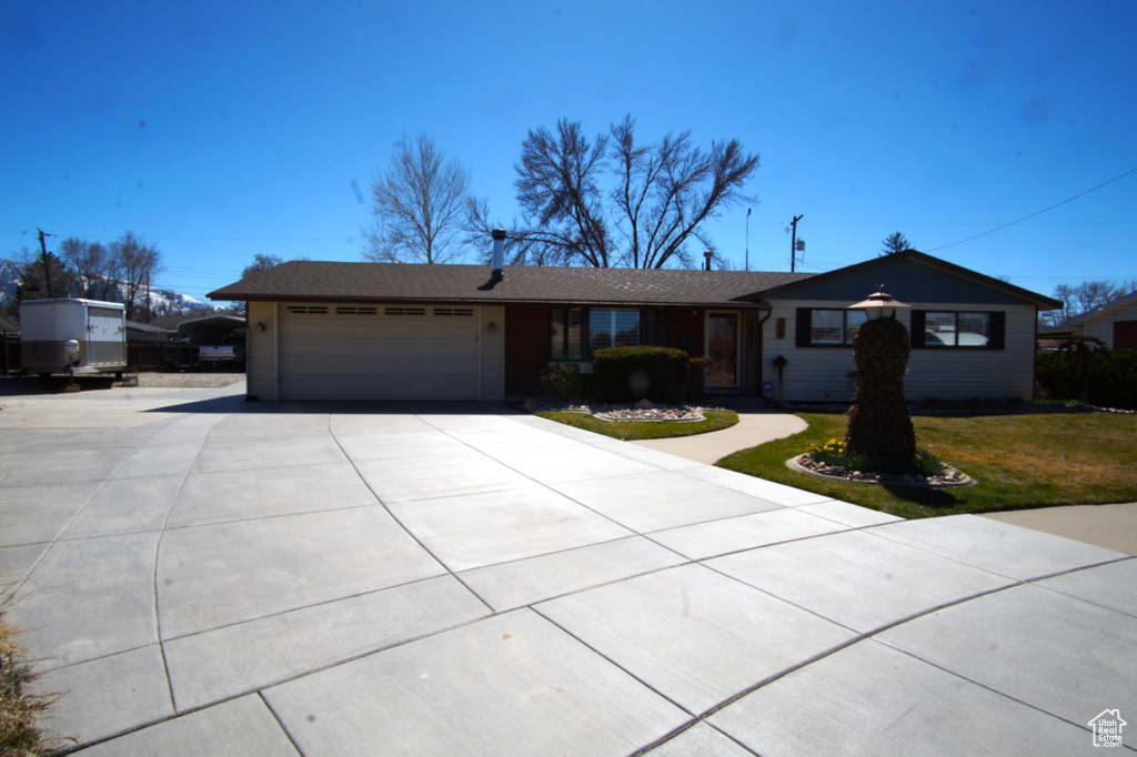 Ranch-style house with an attached garage, concrete driveway, and a front yard