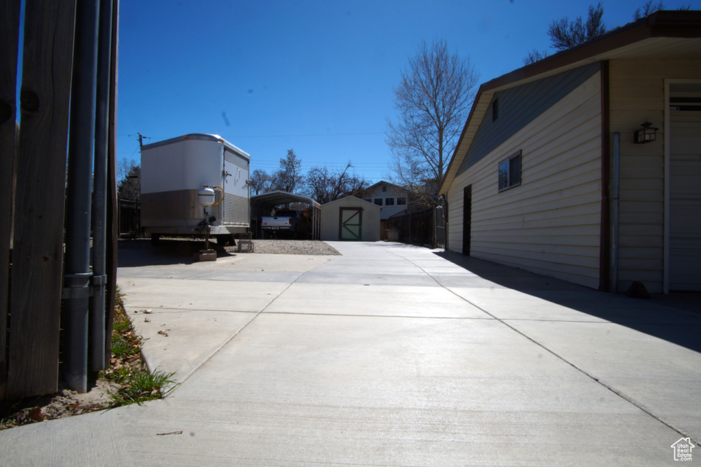 View of patio / terrace with a storage unit, a detached carport, an outbuilding, and driveway