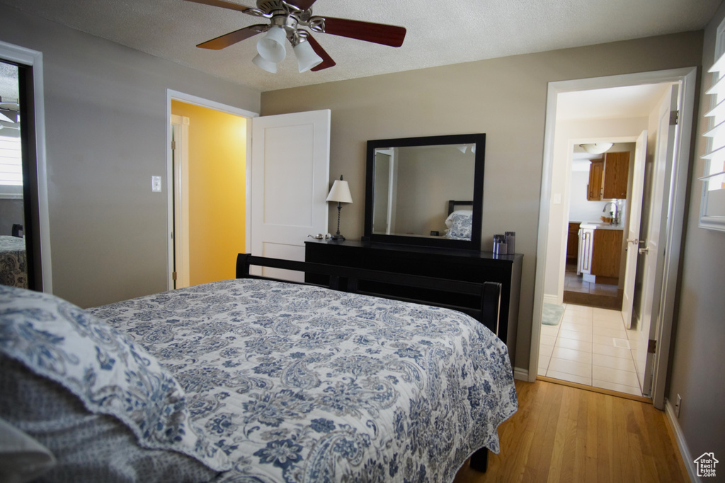 Bedroom with baseboards, light wood-type flooring, ceiling fan, and a textured ceiling