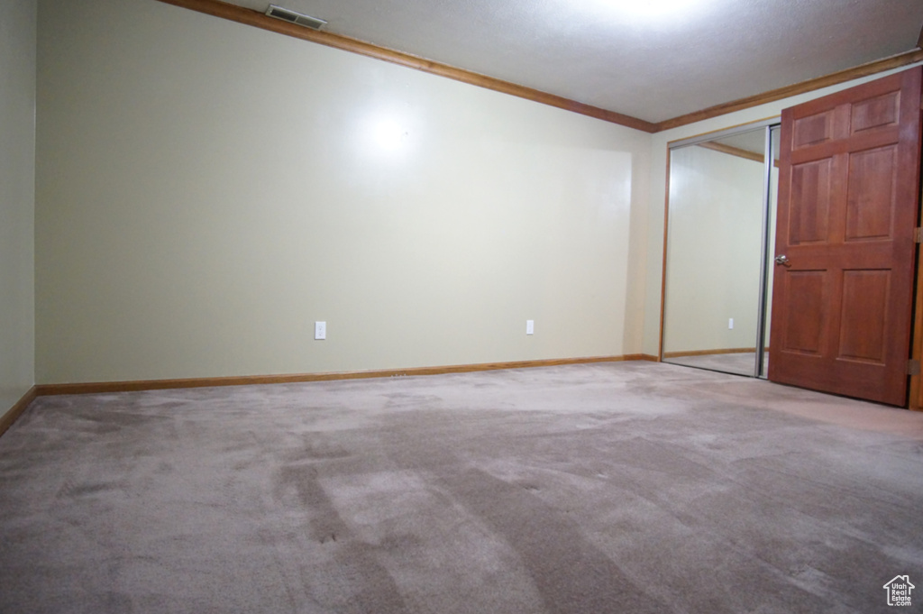Unfurnished bedroom with ornamental molding, carpet, baseboards, and visible vents
