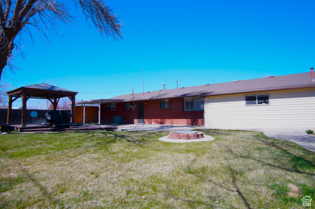 Back of house featuring a fire pit, a gazebo, a patio, and a yard