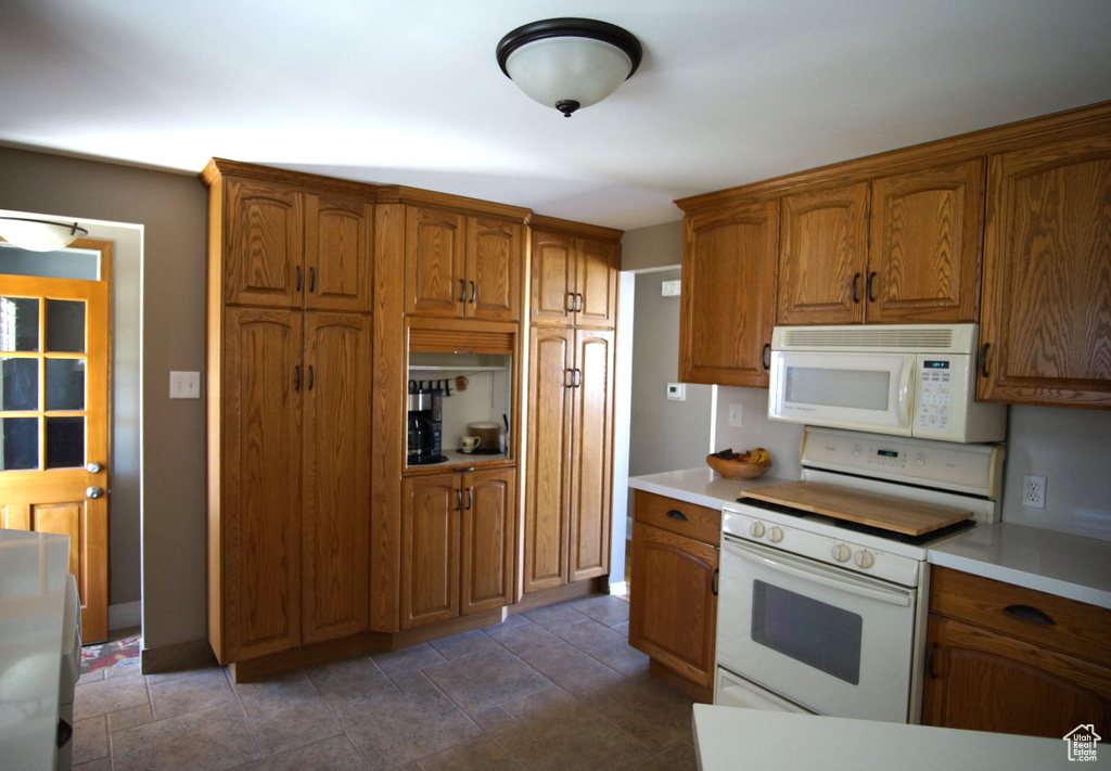 Kitchen featuring white appliances, light countertops, and brown cabinets