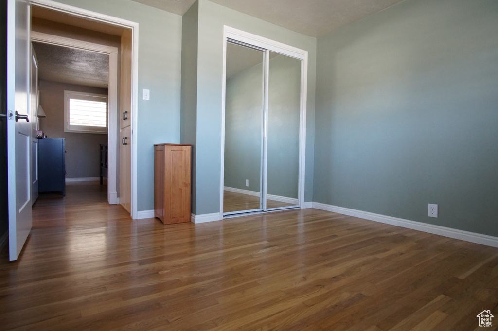 Unfurnished bedroom featuring baseboards, a closet, and wood finished floors