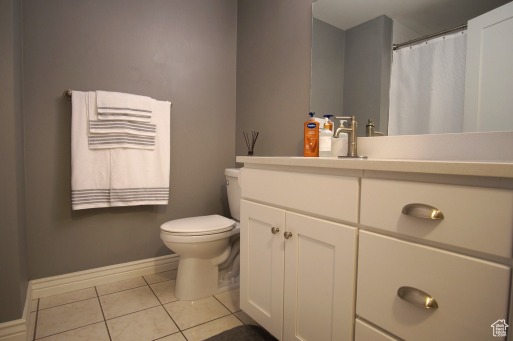 Bathroom with vanity, toilet, a shower with shower curtain, baseboards, and tile patterned floors