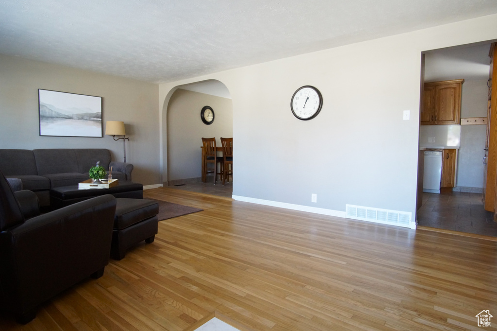 Living area featuring arched walkways, baseboards, light wood finished floors, and visible vents