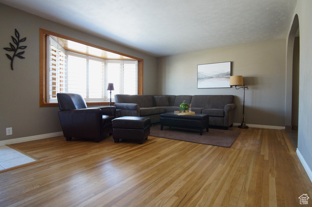 Living area with arched walkways, baseboards, and light wood finished floors