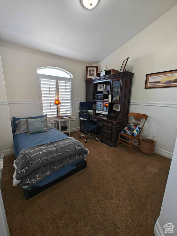 Carpeted bedroom featuring wainscoting
