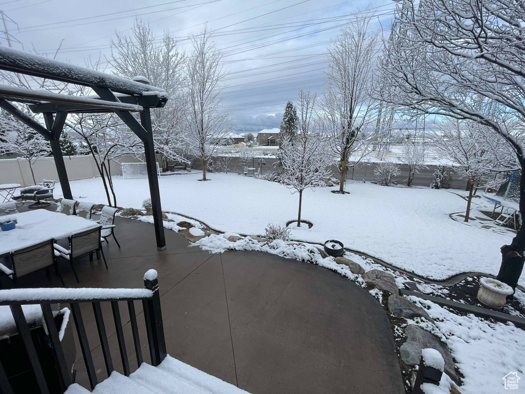 Yard layered in snow with fence, outdoor dining space, and a patio