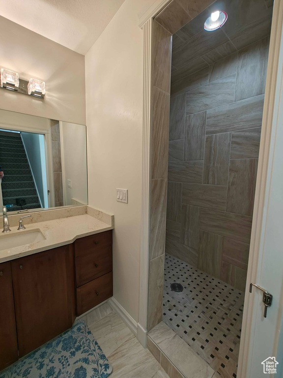 Full bath featuring baseboards, tiled shower, and vanity