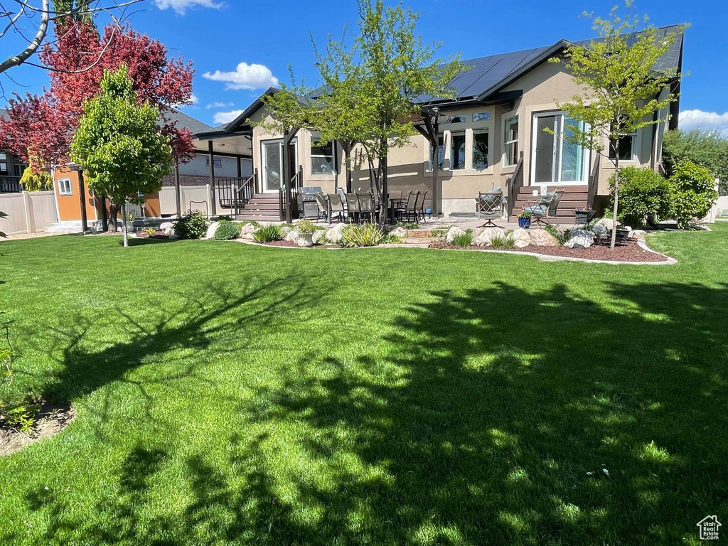 Back of property featuring entry steps, stucco siding, roof mounted solar panels, and a patio area