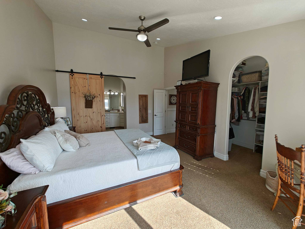 Bedroom with arched walkways, carpet, recessed lighting, ensuite bathroom, and a spacious closet