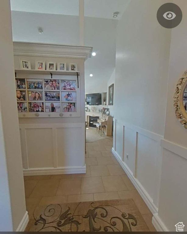 Corridor featuring wainscoting, light tile patterned floors, and a decorative wall