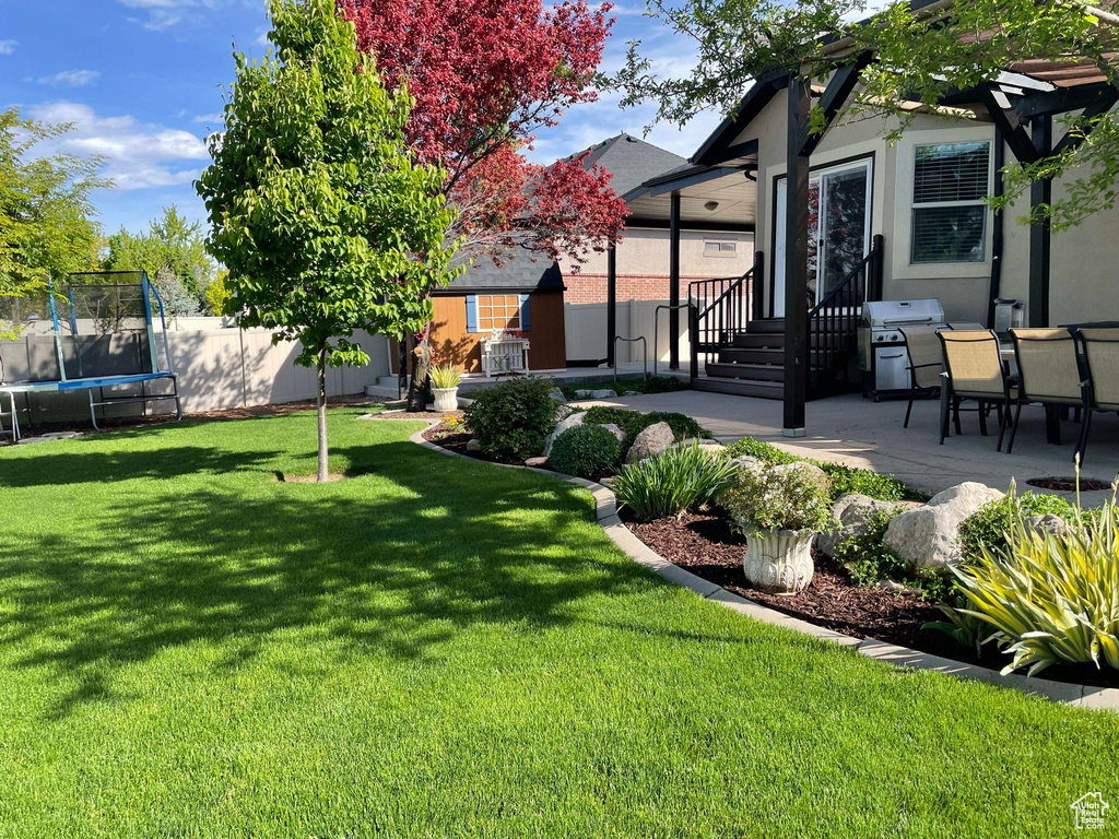 View of yard featuring a trampoline, a patio area, fence, and entry steps
