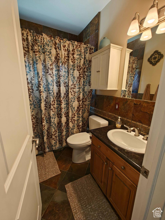Full bathroom featuring vanity, backsplash, toilet, and curtained shower