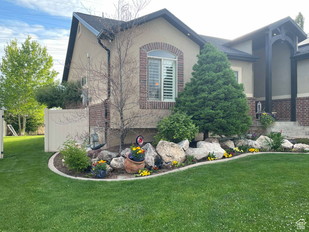 View of property exterior with a lawn, brick siding, and stucco siding