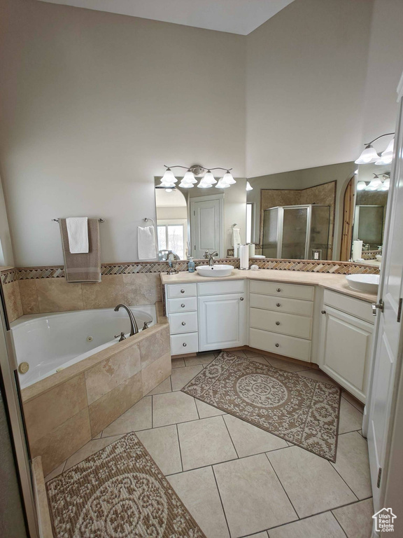 Bathroom featuring a high ceiling, vanity, tile patterned floors, a jetted tub, and a shower stall