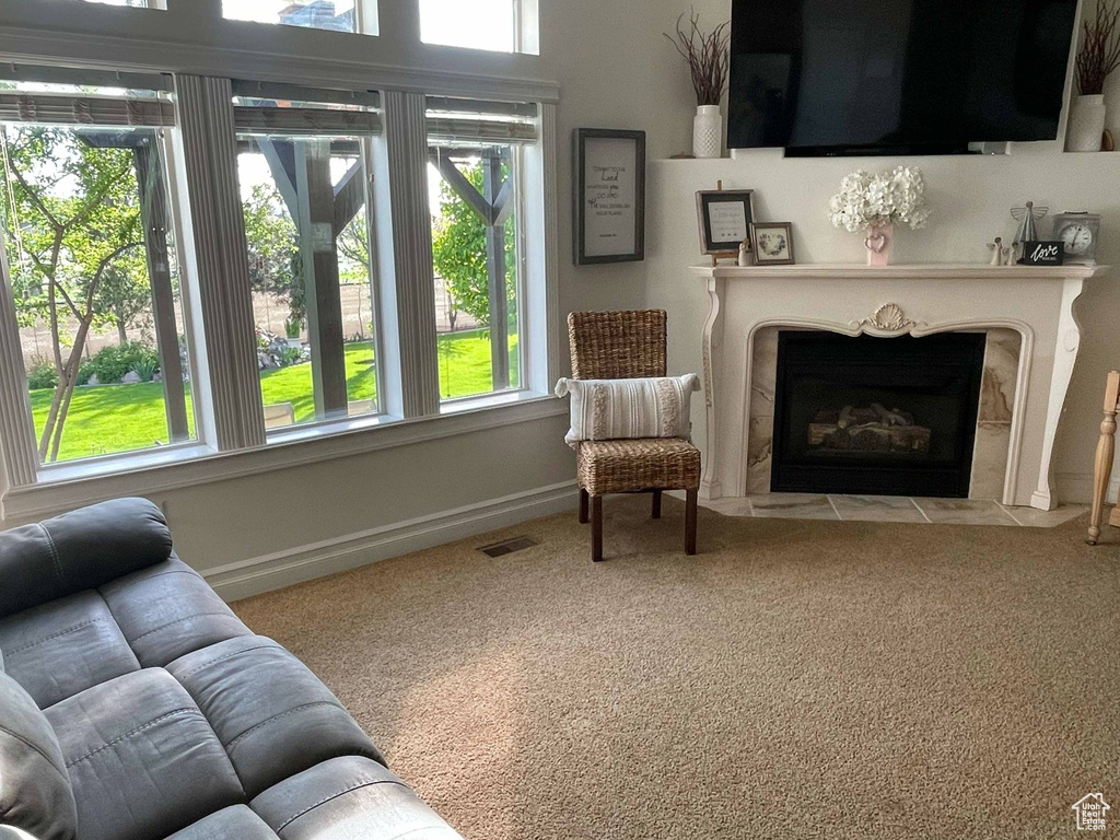 Carpeted living room with a fireplace with flush hearth, baseboards, and visible vents