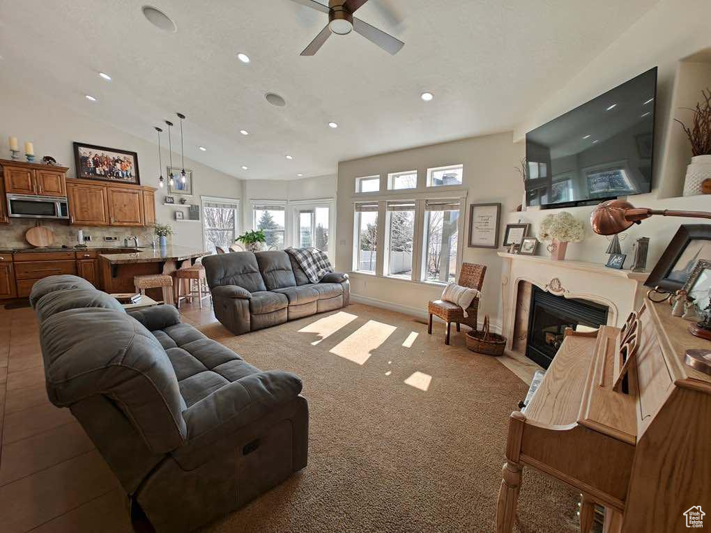 Living area featuring vaulted ceiling, a ceiling fan, recessed lighting, and a fireplace with flush hearth