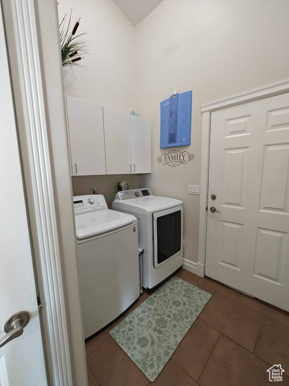 Washroom featuring cabinet space, light tile patterned floors, baseboards, and washer and clothes dryer