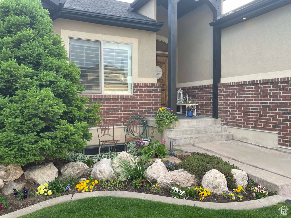 Exterior details featuring a shingled roof, stucco siding, and brick siding