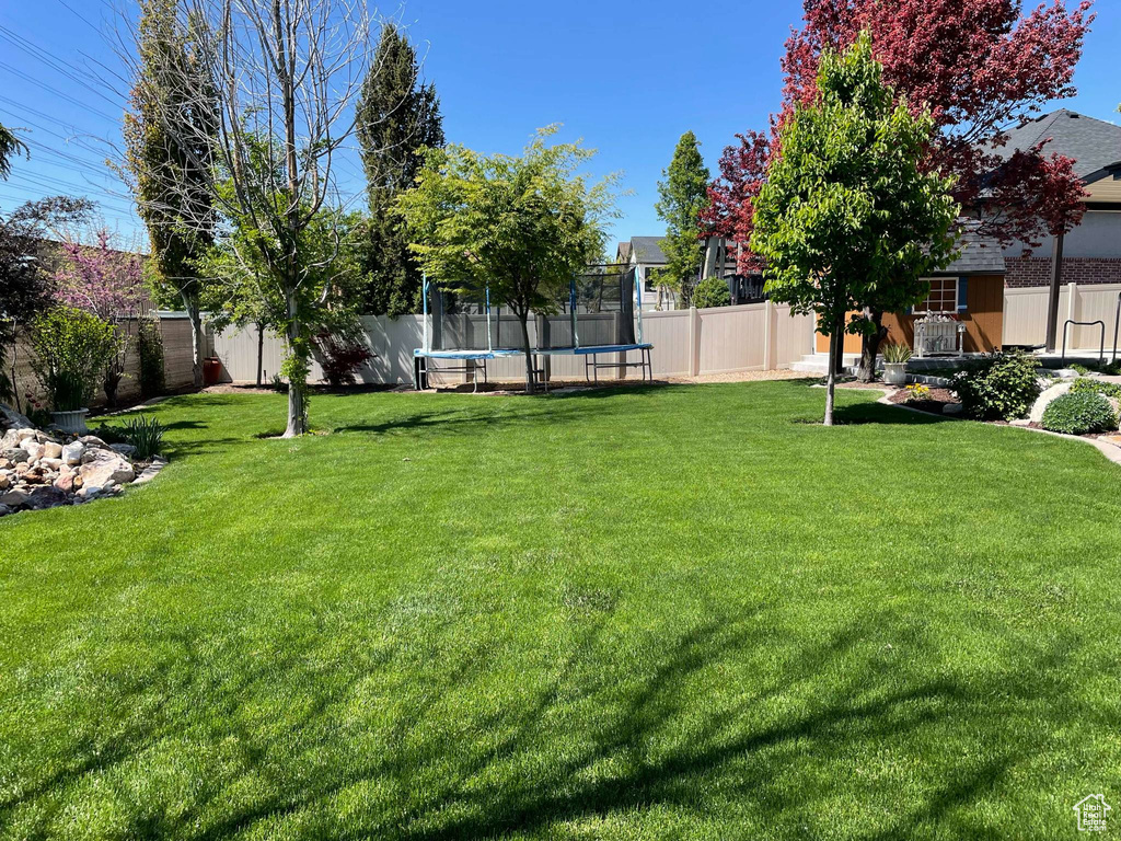 View of yard with a fenced backyard and a trampoline