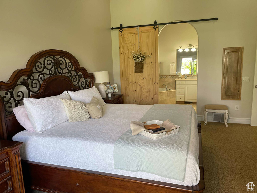 Carpeted bedroom featuring arched walkways, baseboards, and ensuite bathroom
