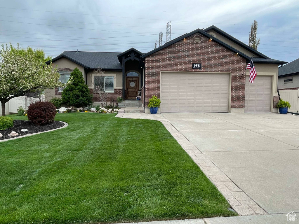 Single story home featuring brick siding, a garage, a front yard, and concrete driveway