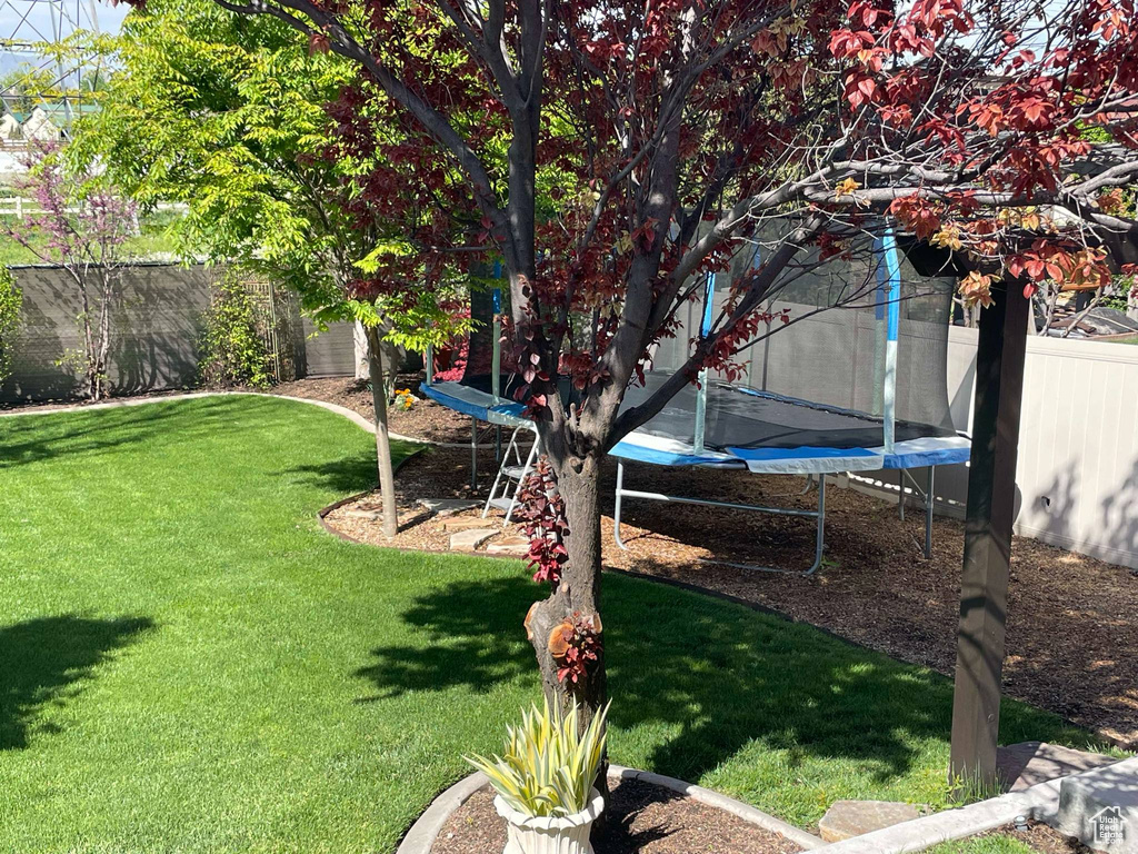 View of yard with a fenced backyard and a trampoline